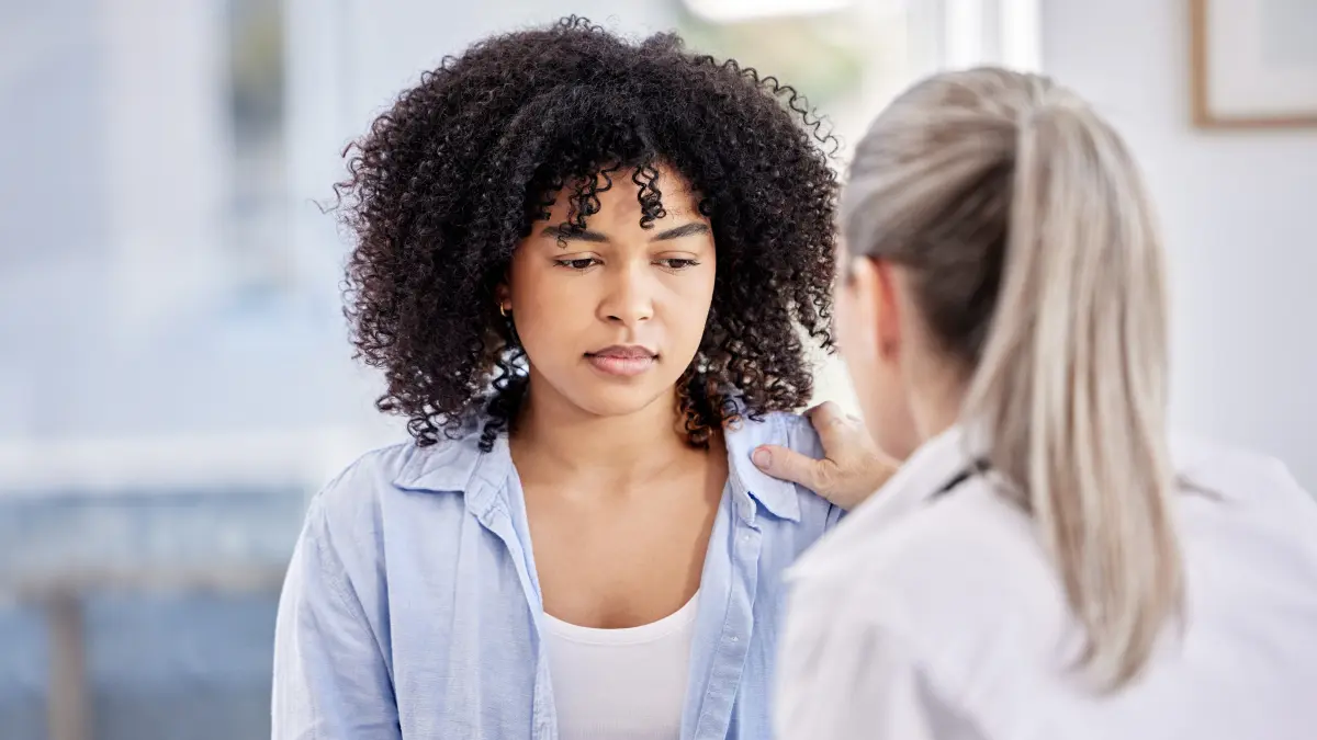 Ärztin legt Patientin tröstend die Hand auf die Schulter – Symbolbild für psychoonkologische Begleitung und Nachsorge bei Brustkrebs (Mammakarzinom)