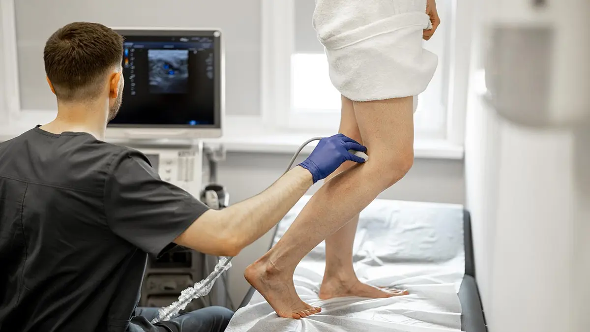 Arzt untersucht Bein einer Patientin mit Ultraschall zur