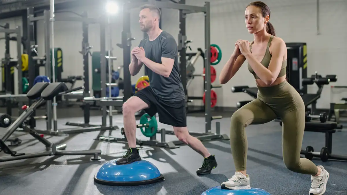 Eine junge Frau und ein junger Mann trainieren ihre Balance in einem Fitnessstudio.