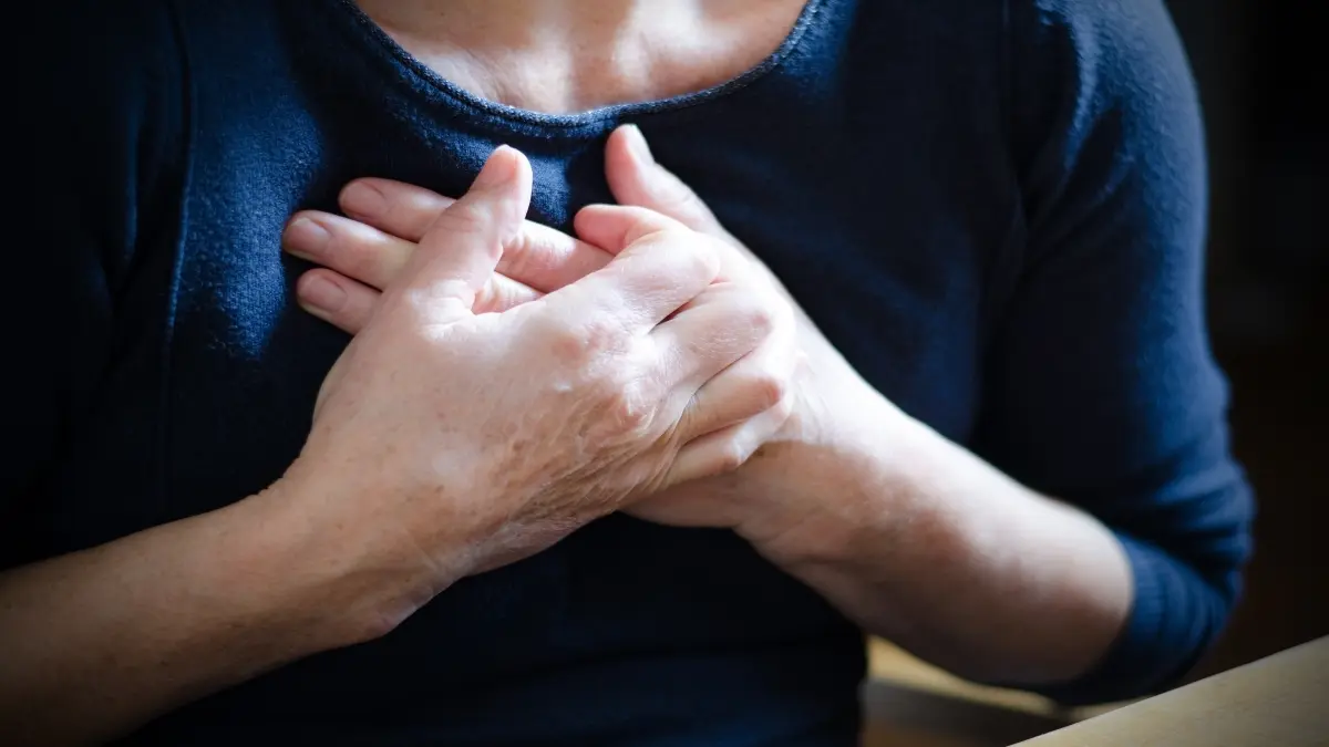 Person hält sich mit beiden Händen die Brust – Symbolbild für Brustschmerzen und Angina-pectoris-ähnliche Beschwerden