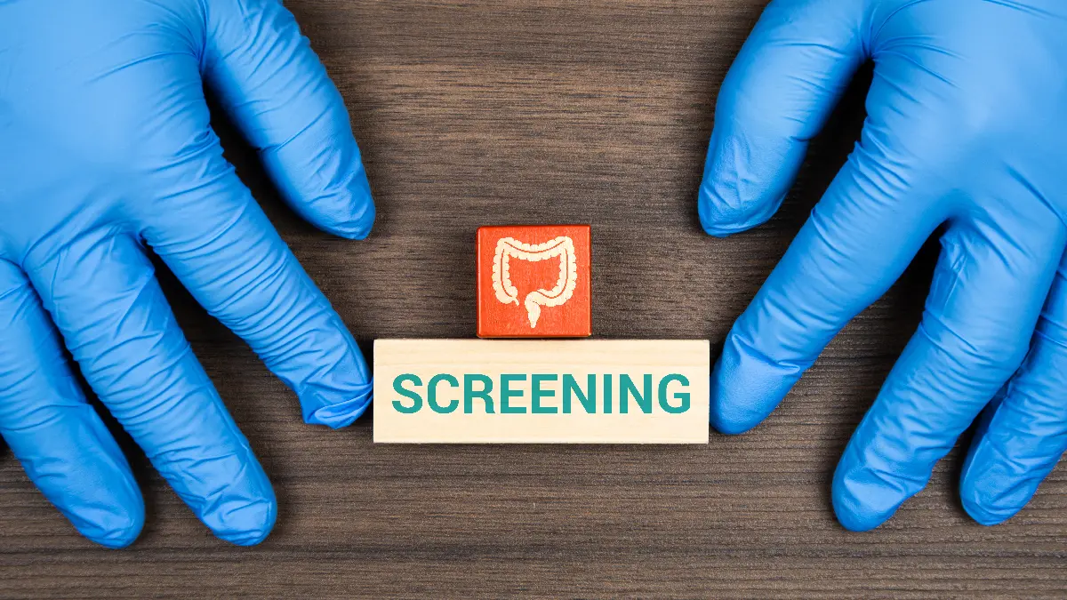 Medizinische Handschuhe umgeben Holzblock mit Darmkrebs-Screening Symbol