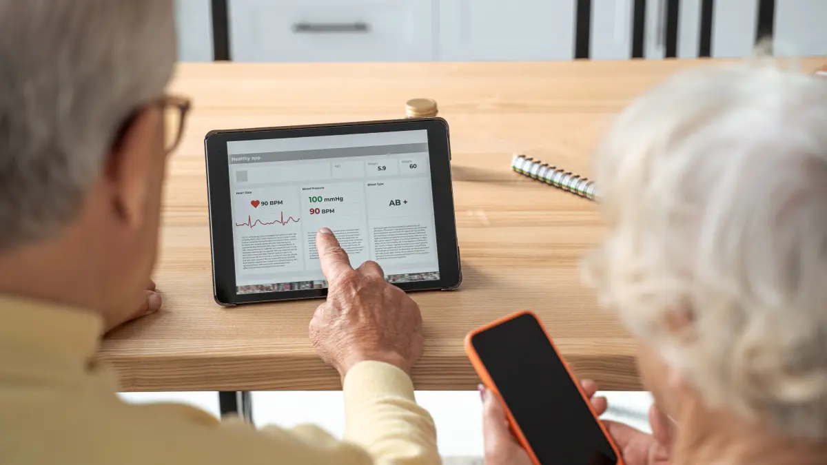 Älteres Paar nutzt gemeinsam eine kardiologische Gesundheits-App auf einem Tablet zur Kontrolle von Herzfrequenz und Blutdruck