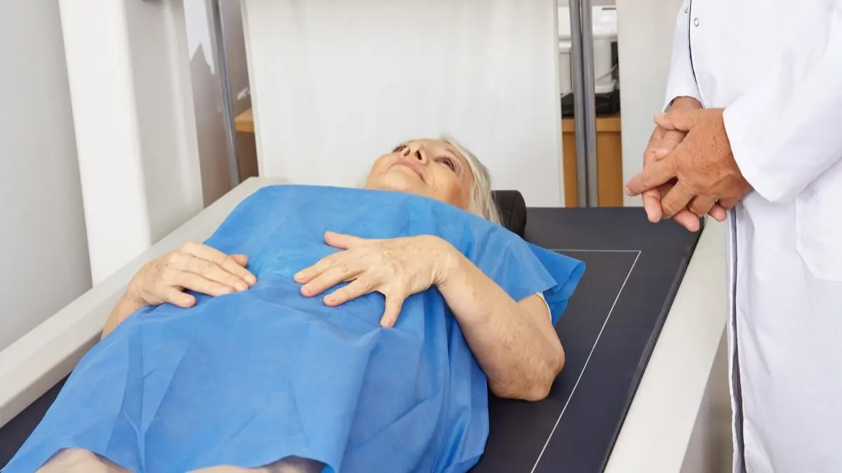 Person liegt auf einer Untersuchungsliege waehrend einer Knochendichtemessung zur Osteoporose Frueherkennung