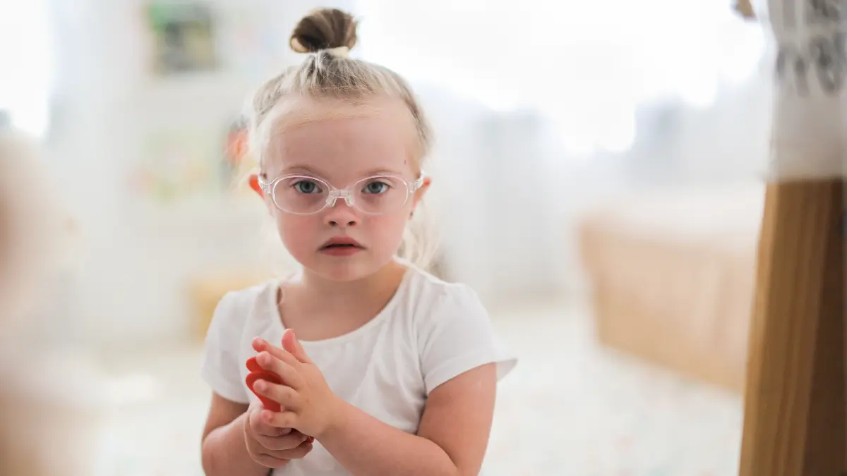Kind mit Brille in heller Umgebung blickt in die Kamera