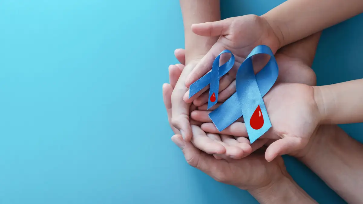 Mehrere Händepaare liegen übereinander und halten zwei blaue Diabetes Awareness Schleifen mit einem roten Blutstropfen darauf.