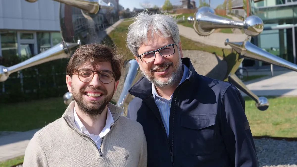 Zwei Forschende stehen vor einem Forschungsgebaeude und laecheln in die Kamera