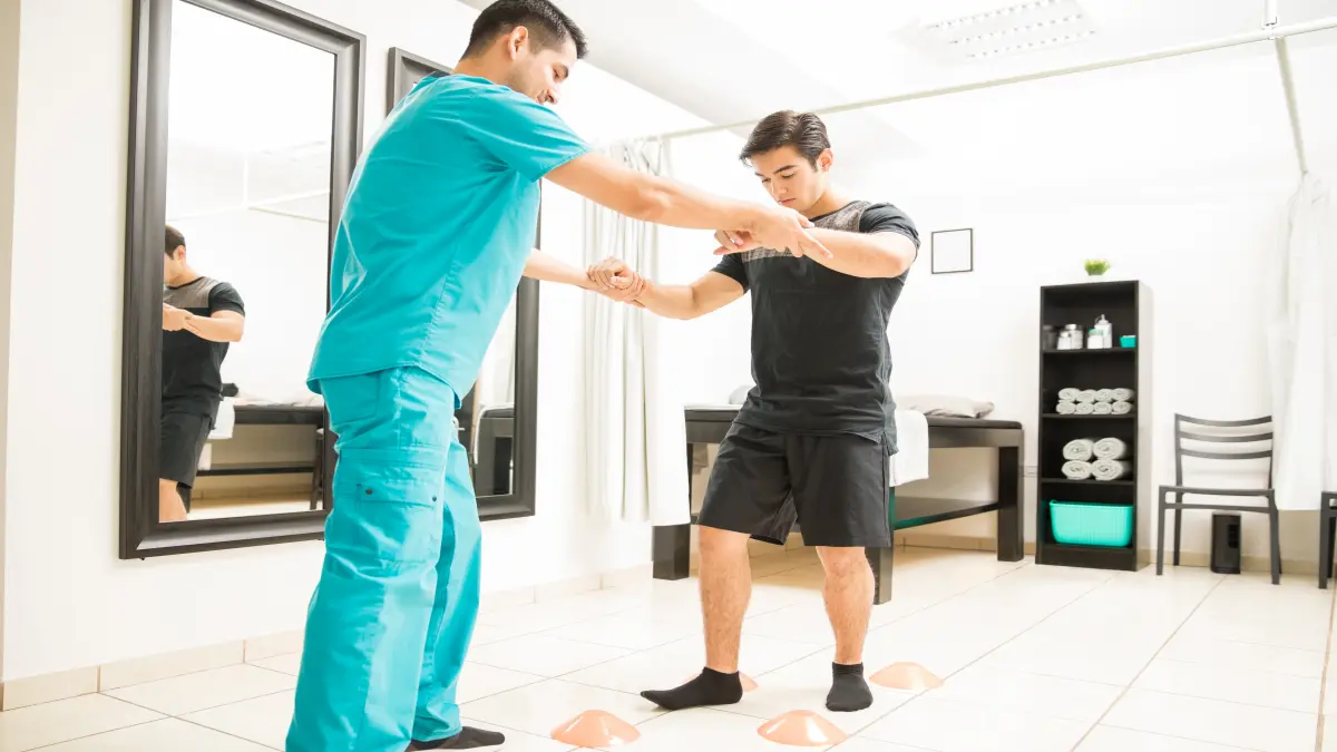 Physiotherapeut unterstützt Patient mit Friedreich-Ataxie beim Gleichgewichts- und Koordinationstraining in einer modernen Therapiepraxis