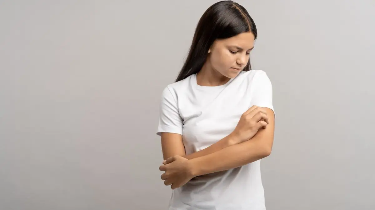 Junge Person kratzt sich am Unterarm als Symbol fuer atopische Dermatitis und fruehe Antikoerpertherapien im Saeuglings und Kleinkindalter