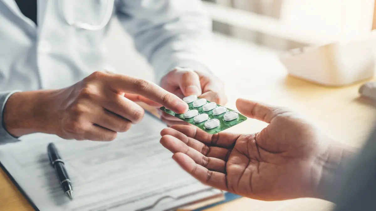 Arzt übergibt einem Patienten einen grünen Blister mit weißen Tabletten während einer medizinischen Beratung