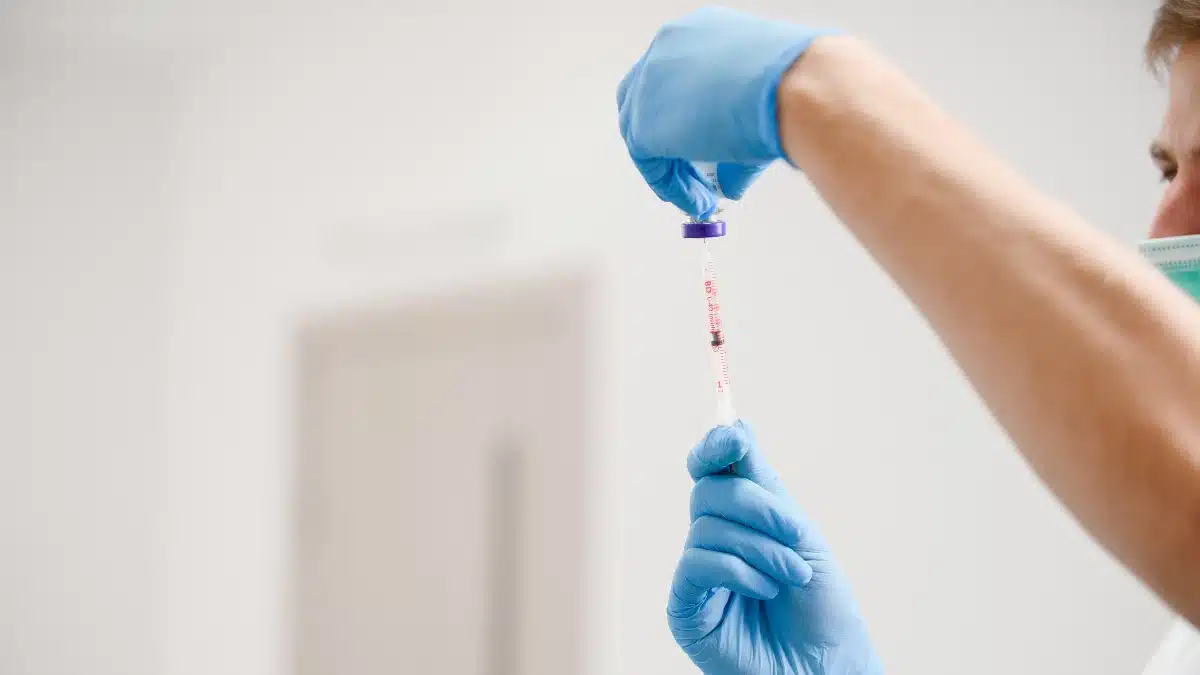 Medizinisches Fachpersonal mit blauen Handschuhen zieht Botulinumtoxin in eine Spritze auf