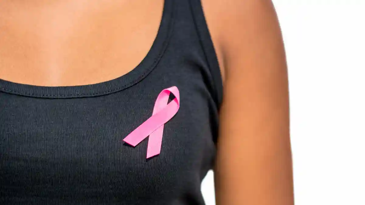 Nahaufnahme eines schwarzen T-Shirts mit einer rosa Schleife auf der Brust einer Frau.