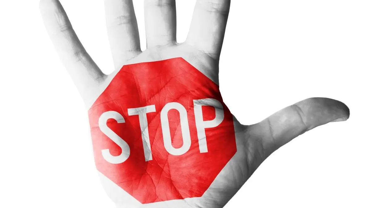 Offene Handflaeche mit rotem Stoppschild und dem Wort STOP als klares Zeichen gegen Machtmissbrauch und sexuelle Belaestigung