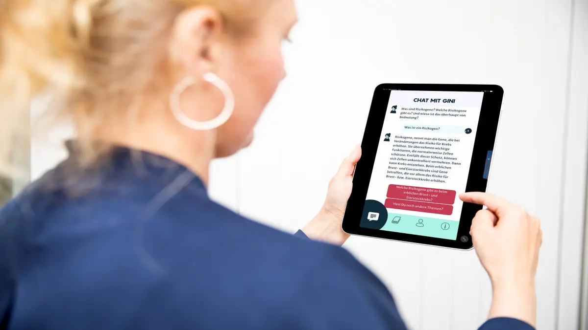 Frau haelt ein Tablet mit einer Chat-App zur GenE3-Anwendung fuer digitale Unterstuetzung bei erblichem Krebs