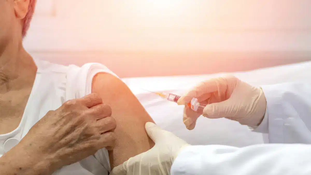 Arzt verabreicht älterem Patienten eine Impfung – Influenza- und COVID-19-Impfung zur kardiovaskulären Prävention