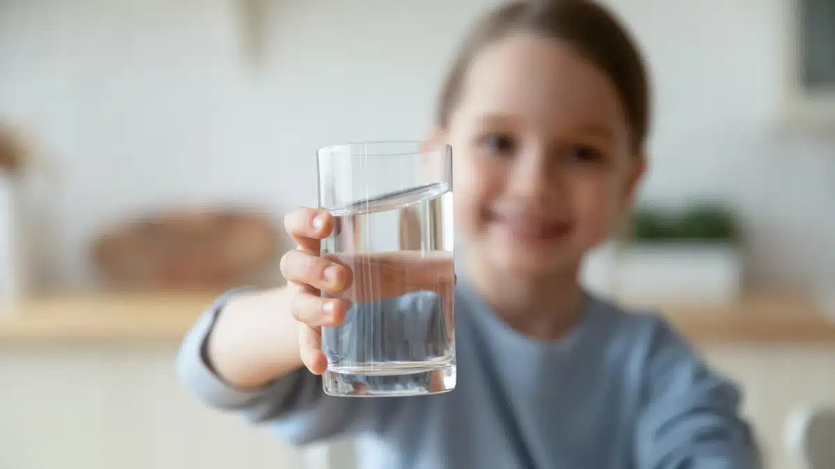 Kind hält Wasserglas in die Kamera – Symbol für kindgerechte orale Medikamenteneinnahme bei NF1