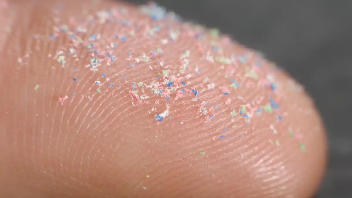 Mikroplastik winzige Plastik Kunststoff Partikel auf Finger auf dem Foto sind in einer Nahaufnahme auf einem Finger Mikroplastikpartikel zu erkennen.