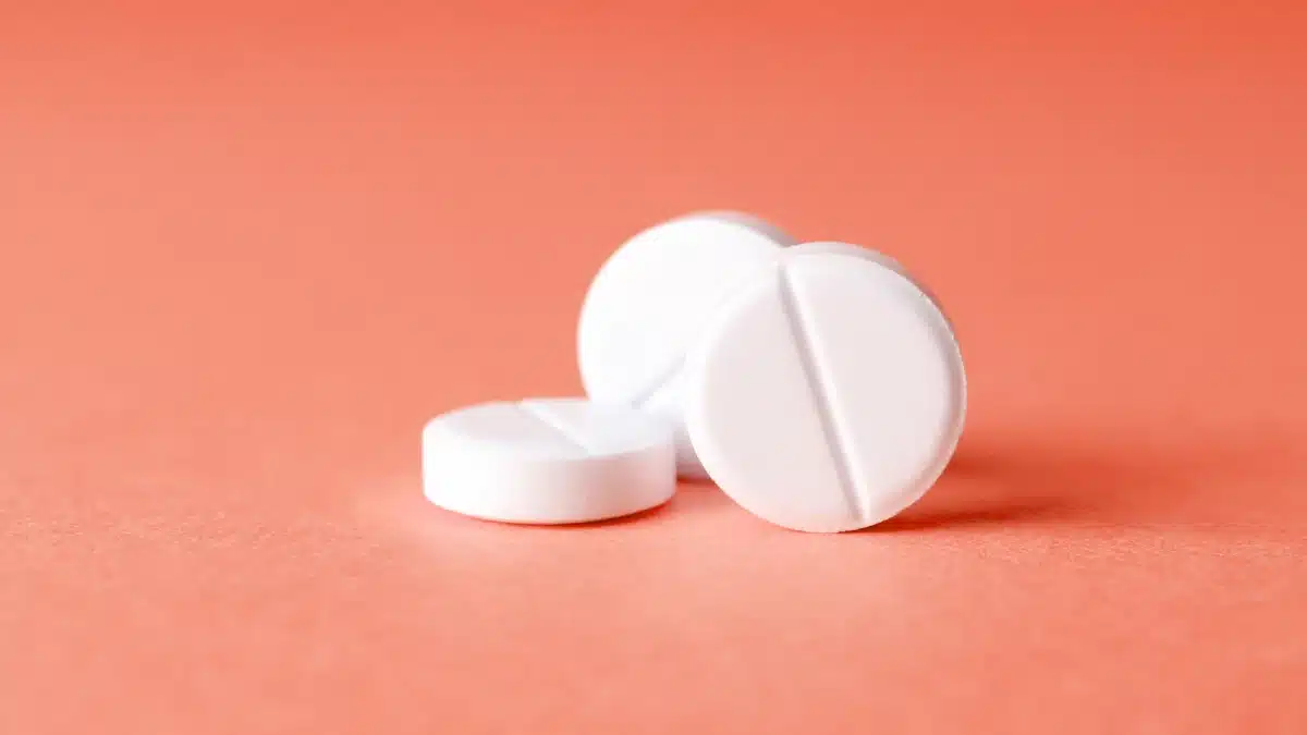 Drei weiße Tabletten auf pfirsichfarbenem Hintergrund