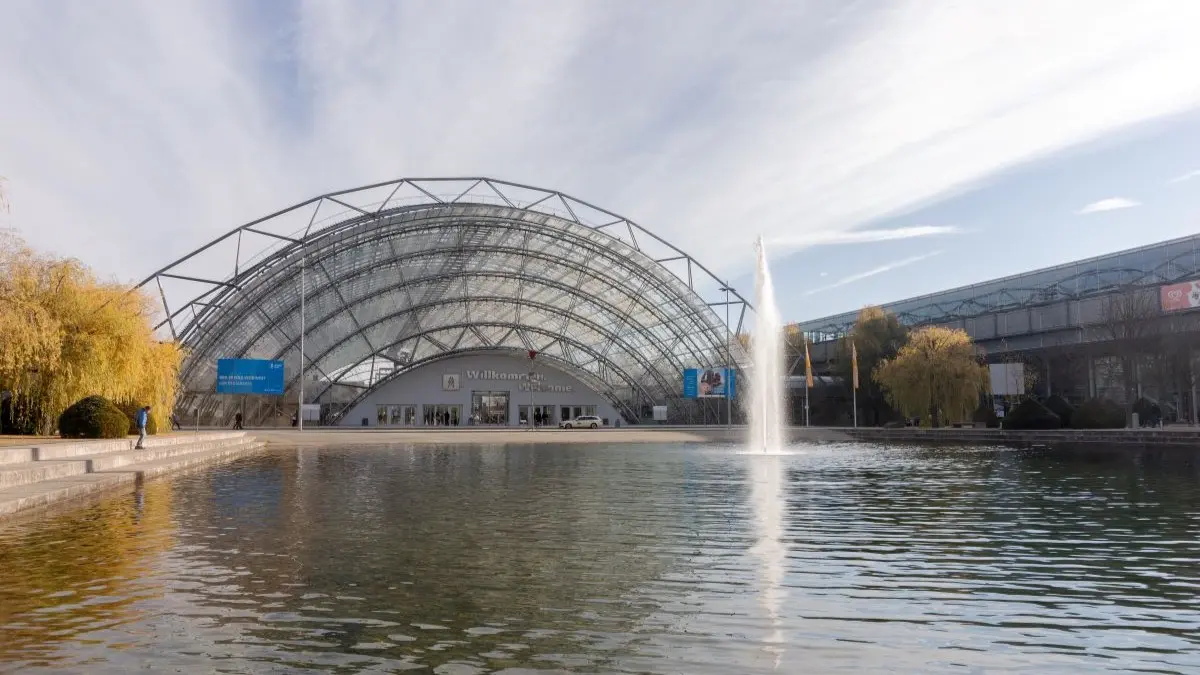 Grosse verglaste Messehalle mit Wasserbecken und Springbrunnen vor dem Eingang, Symbol fuer den Deutschen Hautkrebskongress