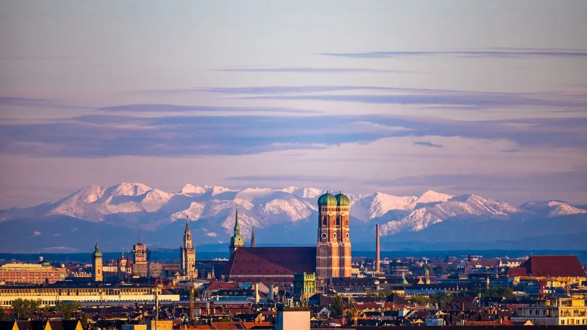 Panorama von Muenchen mit Frauenkirche vor schneebedeckten Alpen bei Sonnenaufgang als Symbol fuer den DGGG Kongress