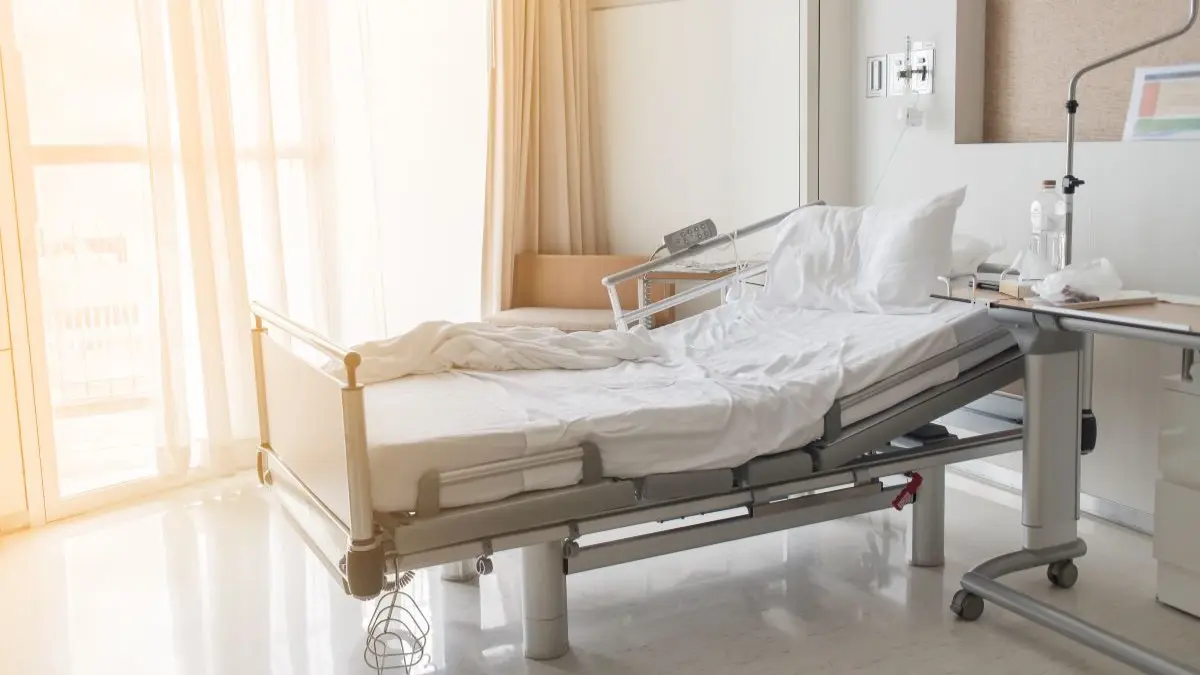 Von Sonne aufgeheiztes Krankenhauszimmer mit leerem Bett als Symbol dafuer, dass die DKG Investitionen in gekuehlte Krankenzimmer fordert