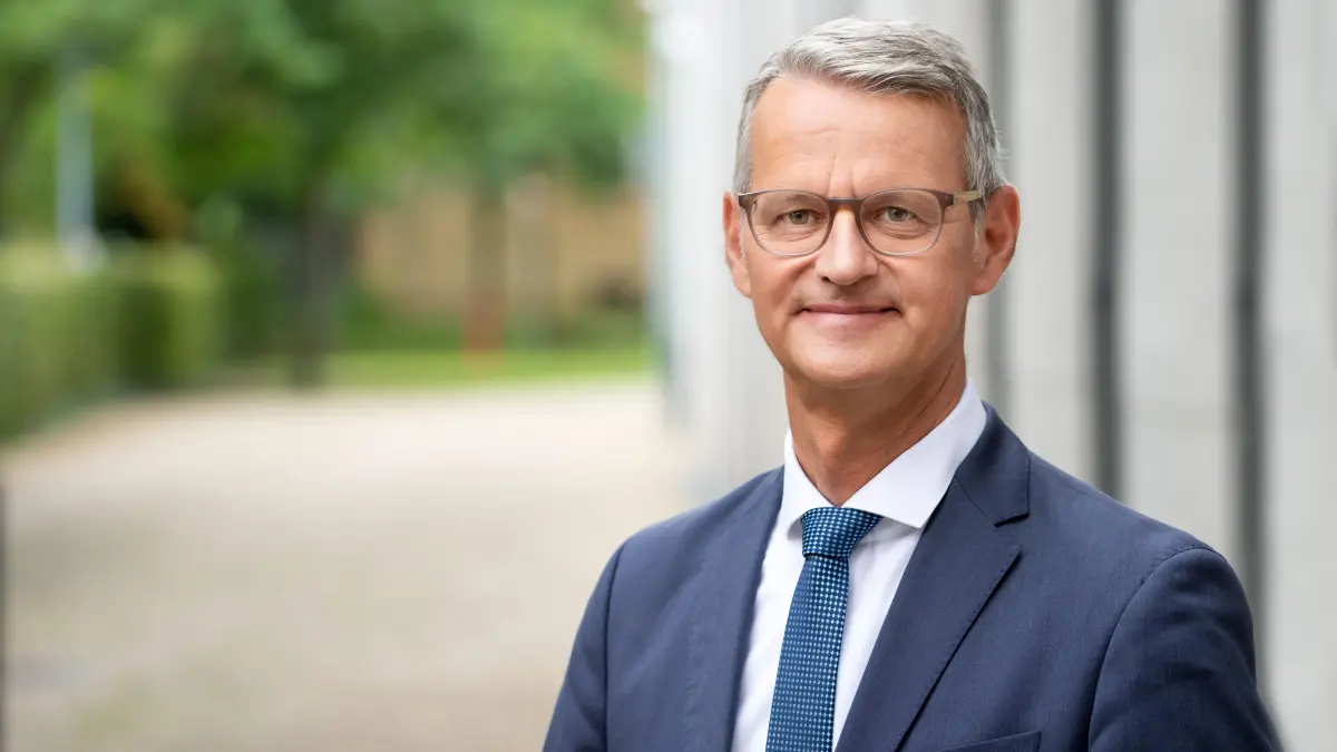Portraet eines aelteren Mannes mit Brille im Anzug vor einem Klinikgebaeude als Symbolbild fuer die Haltung der Krankenhaeuser zu Gewalt im Krankenhaus