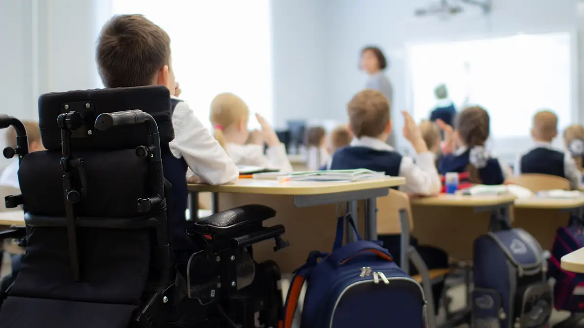 Kind sitzt m Rollstuhl im Schulunterricht