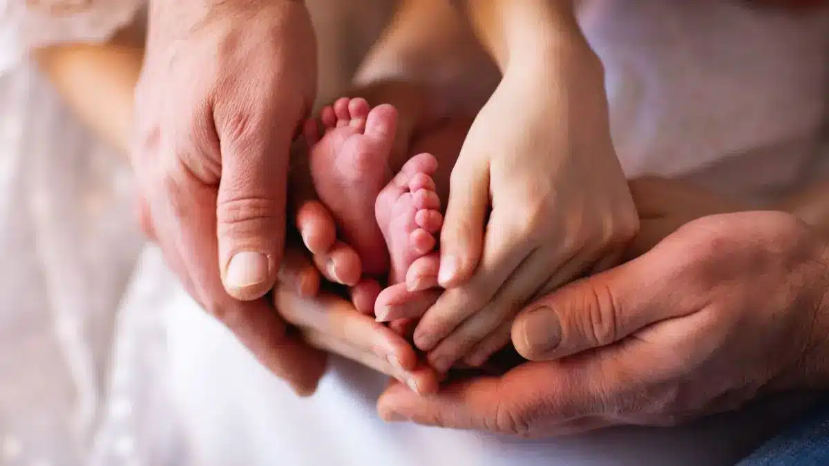 Haende von Eltern umschliessen kleine Babyfuesse als Symbol fuer Kinderwunsch und optimale Versorgung mit Mikronaehrstoffen