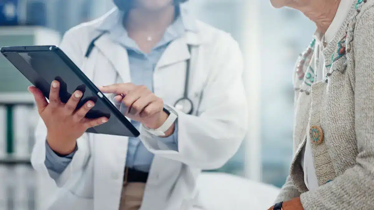 Aerztin erklaert aelterer Patientin auf einem Tablet gesundheitliche Tipps gegen Hitze