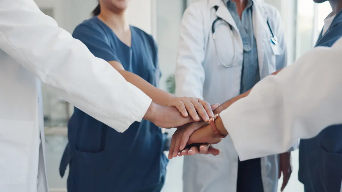 Mehrere Haende von Aerztinnen, Aerzten und Pflegekraeften liegen uebereinander und symbolisieren die interdisziplinaere Zusammenarbeit von Dermatologie und Onkologie