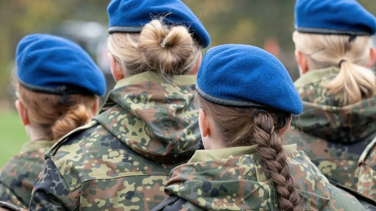 Gruppe von Soldatinnen in Tarnuniform mit blauen Baretts von hinten