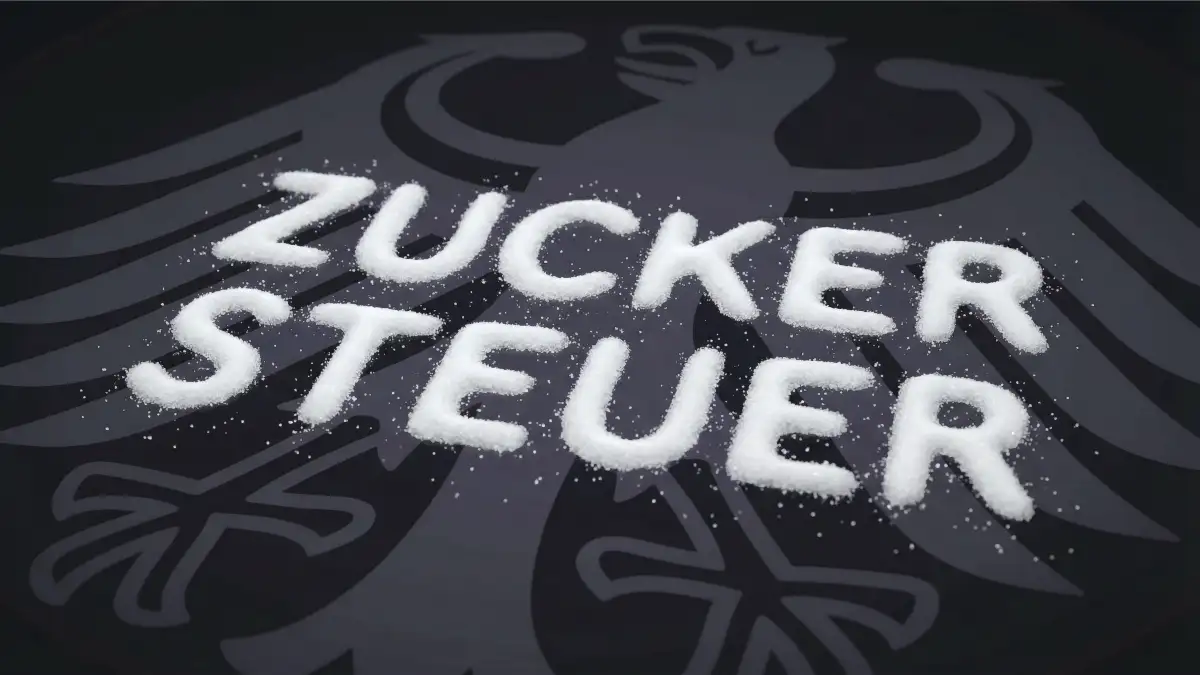 Auf schwarzem Untergrund ist der Bundesadler zu sehen und darauf mit Zucker das Wort "Zuckersteuer" aufgebracht.