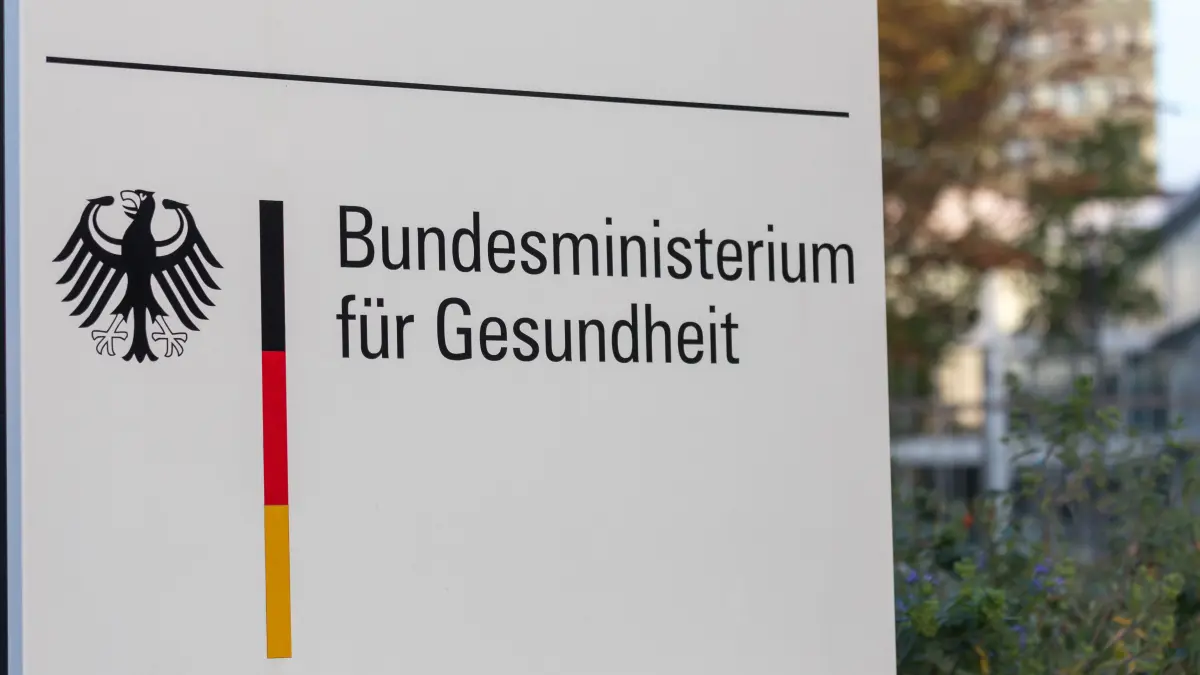 Schild mit der Aufschrift „Bundesministerium für Gesundheit“ vor blauem Himmel mit Wolken