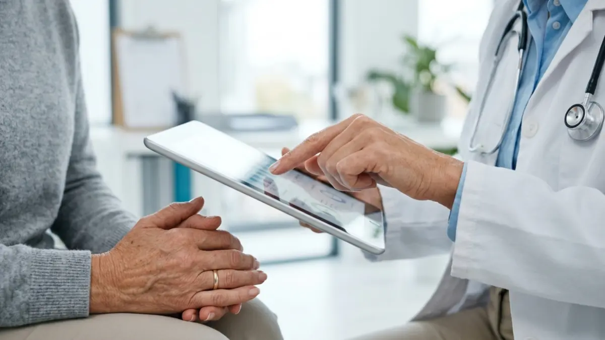 Ärztin zeigt einer älteren Patientin etwas auf einem Tablet