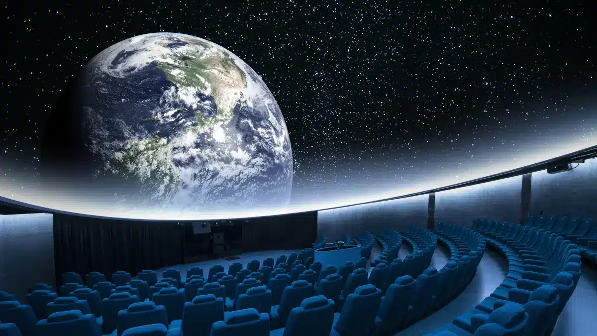 Planetariumskuppel mit Erdprojektion und blauen Sesseln im Zuschauerraum