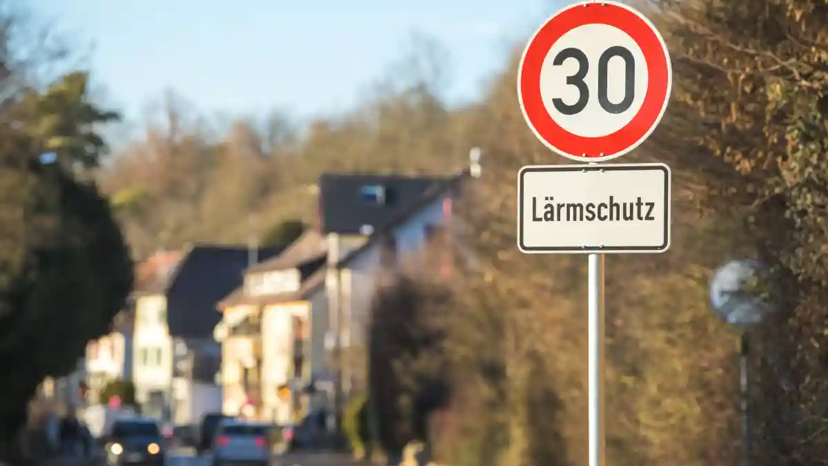Verkehrsschild mit Tempo 30 Lärmschutz an befahrener Straße in einem Wohngebiet