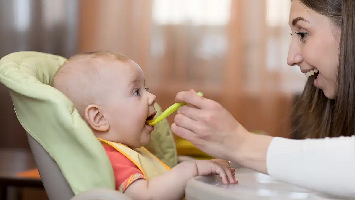 Mutter füttert Baby mit dem Löffel