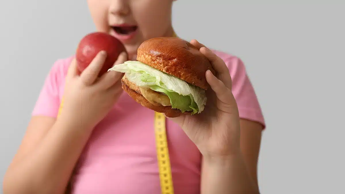 Mädchen mit Adipositas isst Apfel statt Burger
