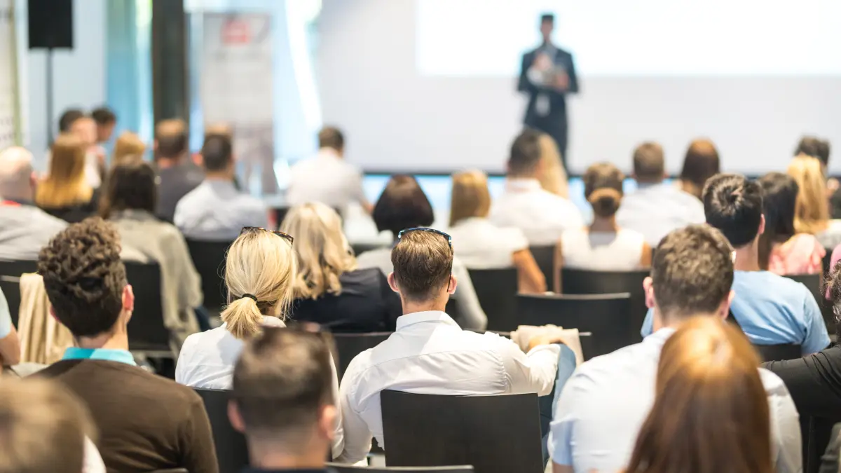 Ein Redner hält einen Vortrag vor Publikum im Konferenzsaal.